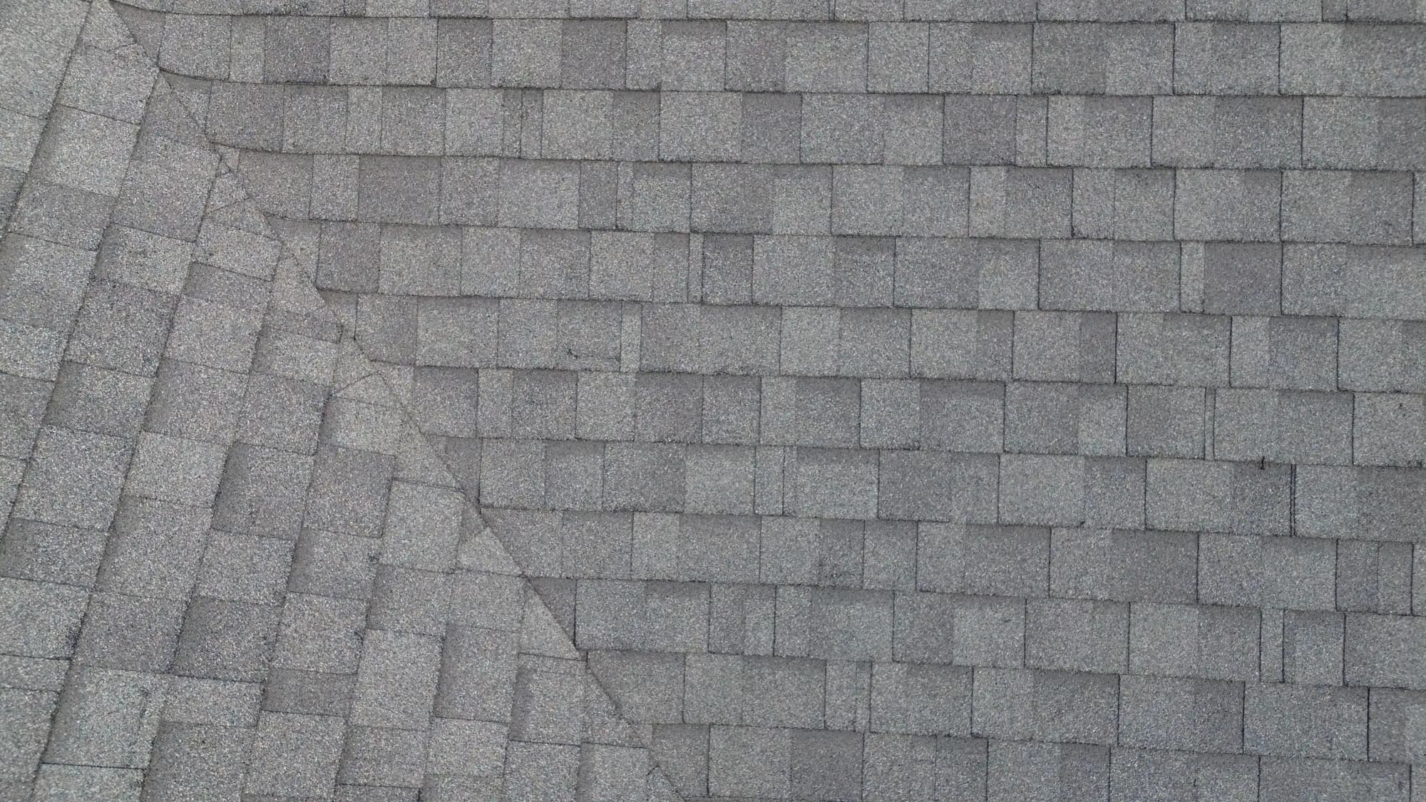 Close-up aerial detail of aged three-tab asphalt shingles showing granule loss and wear
