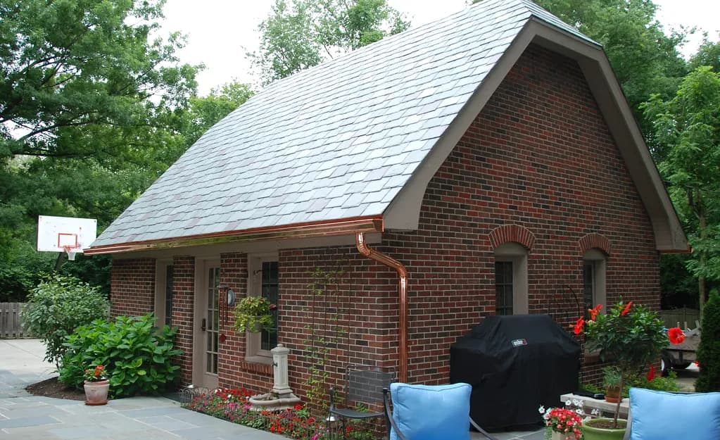 New copper half-round gutter and round copper downspout on a brick cottage