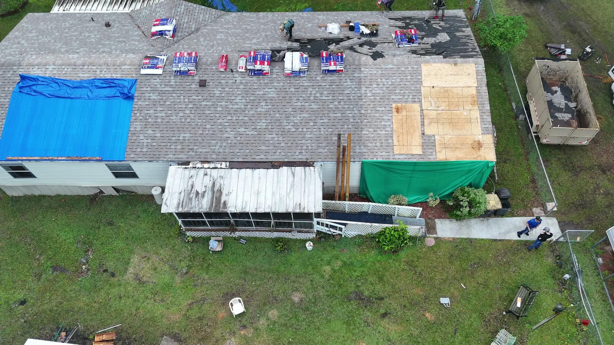 Close aerial of tarped roof sections and new plywood decking, the documentation an insurance claim is built on