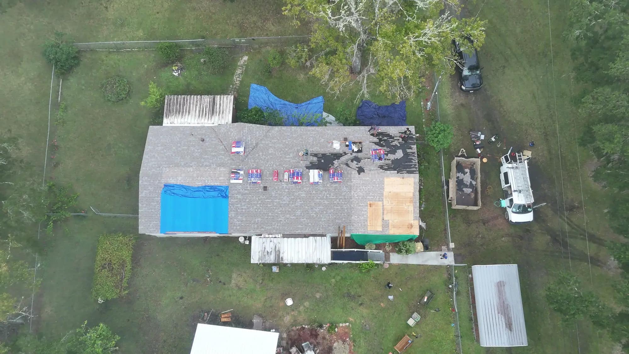 Aerial view of a storm-damaged Jacksonville home with a blue emergency tarp and fresh plywood patch over the damaged roof section